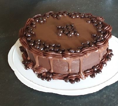 A chocolate cake edged with chocolate balls and a caramel drip
