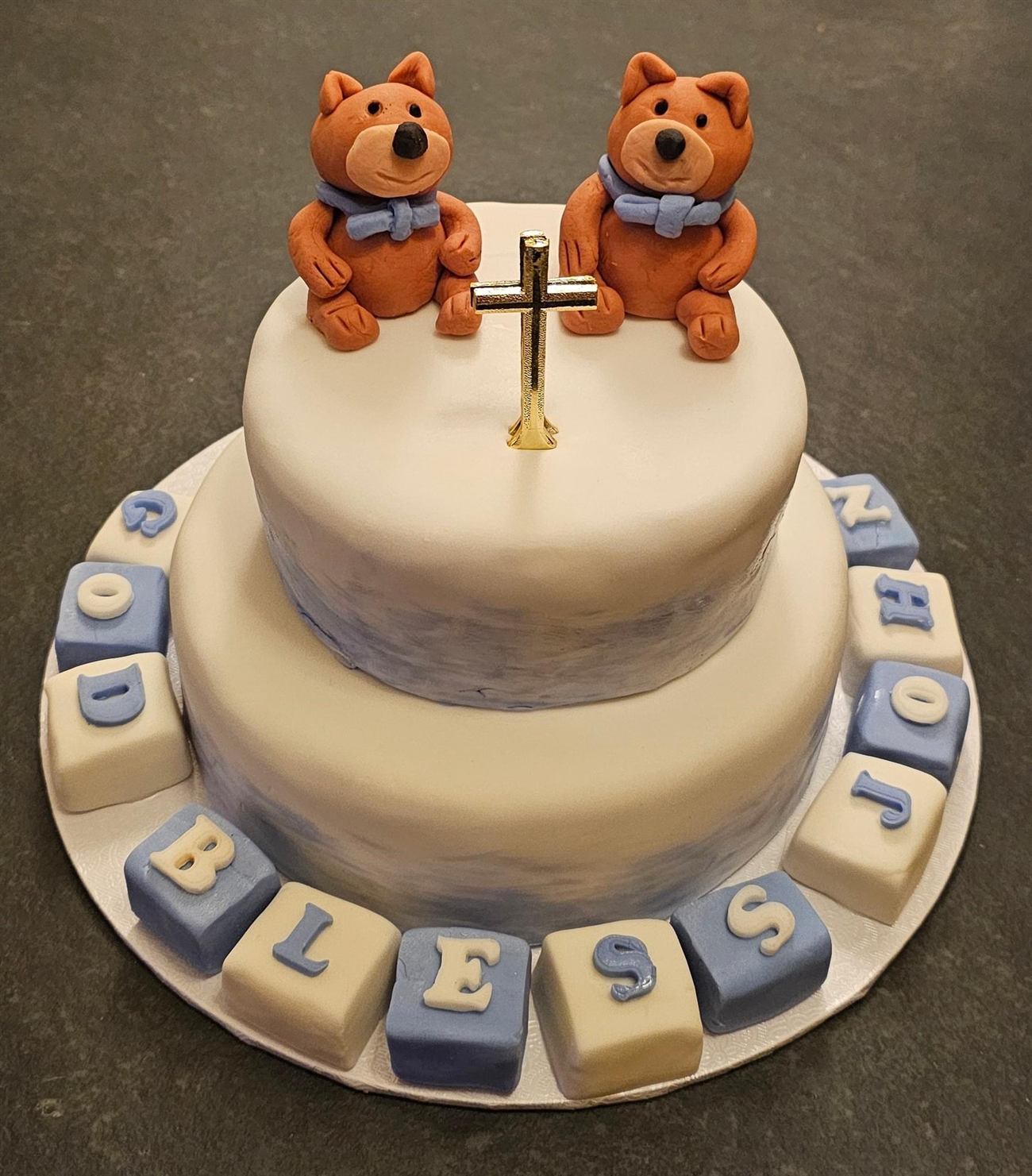 A two-tier christening cake with sugar bears and lettered blocks