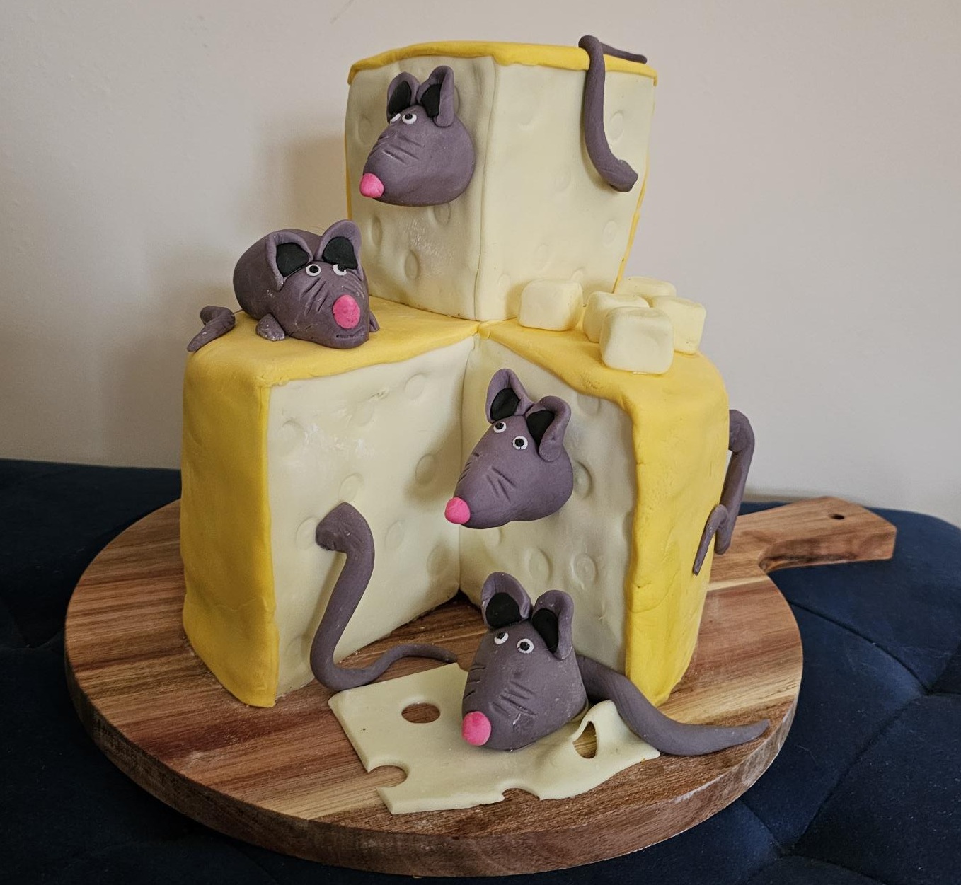 A two-tier cake modelled as a wedge of cheese, climbed over by sugar mice