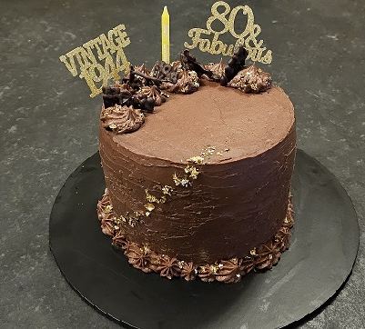 A chocolate cake finished with gold leaf and Vintage 1944 and 80 and Fabulous toppers