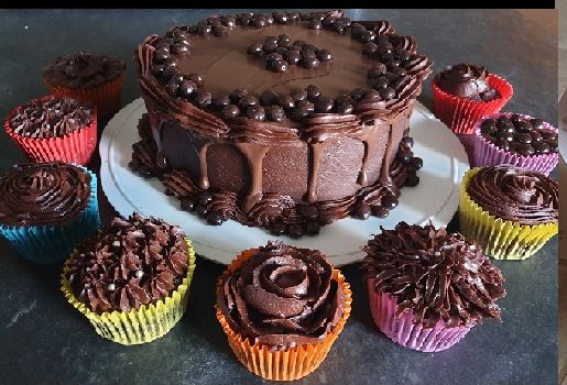 A chocolate cake surrounded by matching chocolate cup cakes in bright cases