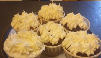 Cup cakes piped with pale buttercream in fluted cases