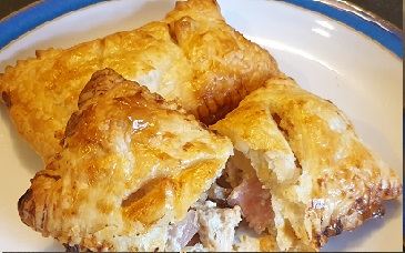 Home-made pasties with a golden puff pastry crust, one cut open