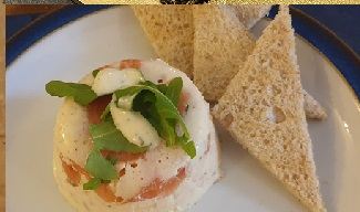 A smoked salmon and rocket starter beside brown bread triangles