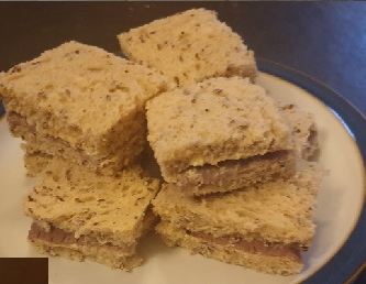 Wholemeal finger sandwiches stacked on a plate